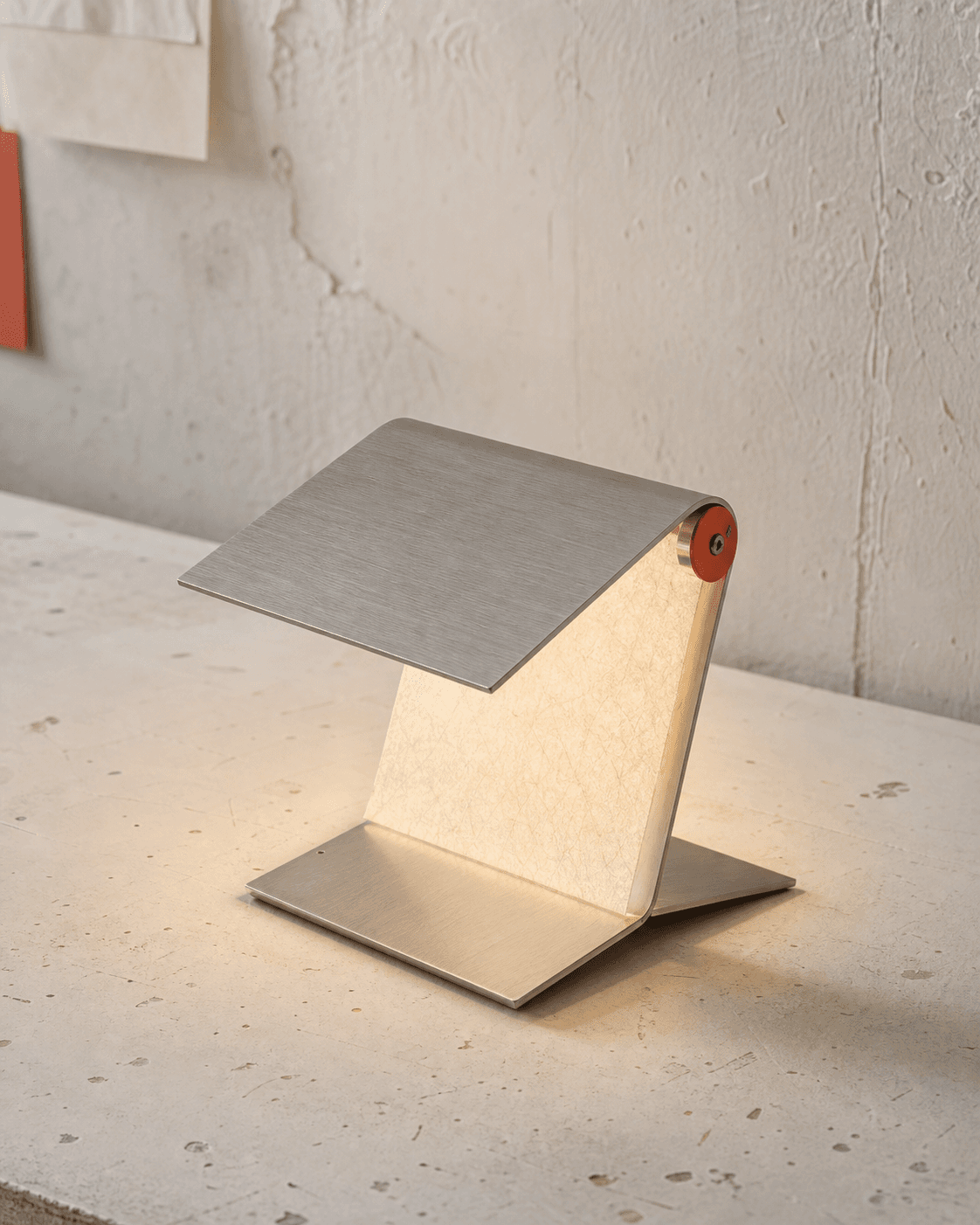 A folded aluminum lamp glowing on a studio workbench